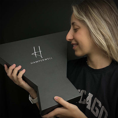 Lady posing and smiling with signature chocolate bouquet packaging exclusive to HamperWell. Top of box with Hamperwell logo