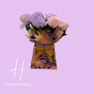 Bouquet of flowers in a decorative box with a yellow ribbon on a purple background, featuring the Hamperwell logo.